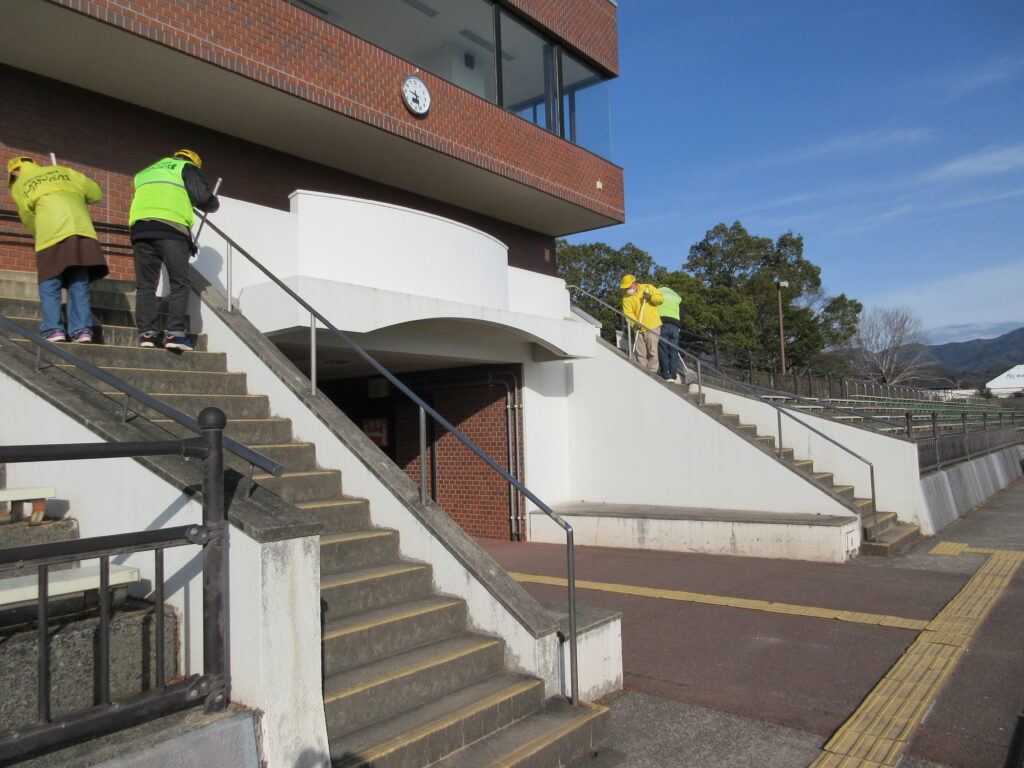 写真。ラグビー・サッカー場を清掃する様子。